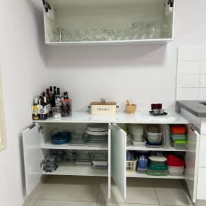 ארון מטבח פתוח עם כוסות, קופסאות פלסטיק וכלי זכוכית.