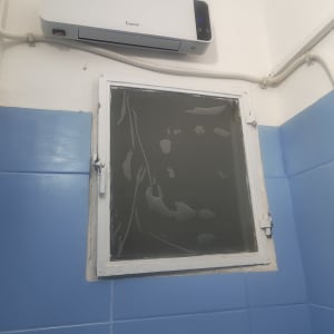 חלון קטן בחדר רחצה שמעליו מותקן מפזר חום