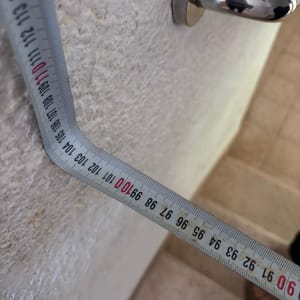 מדידת קיר עם סרט מדידה ליד ידית דלת
