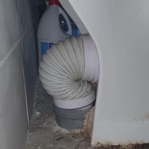 צינור גמיש מחובר לאסלה עם בקבוקי ניקוי ברקע