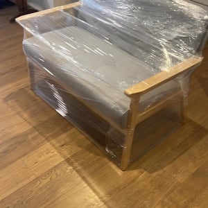 ספה עטופה בניילון נצמד על רצפת עץ