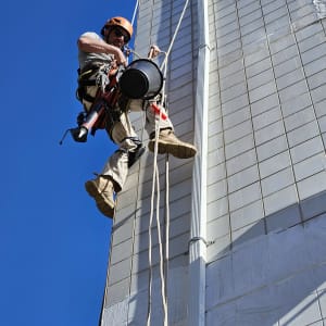 אדם בעבודת גובה על בניין עם ציוד בטיחות