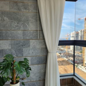 וילון לבן תלוי על חלון זכוכית בפינה