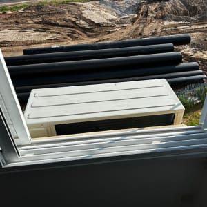 יחידת מזגן חיצונית נראית מחלון פתוח