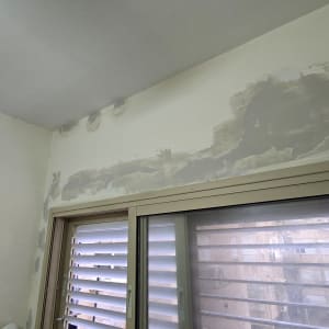 קיר צבוע חלקית עם חלון וכלי עבודה