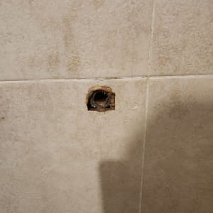 חור בקיר קרמיקה עם צינור חשוף