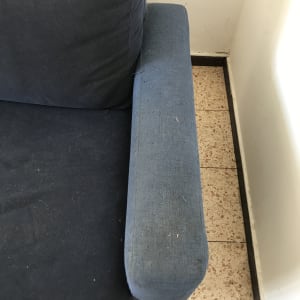 ספה כחולה עם כתמים ולכלוך על הידית