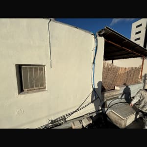 קיר עם חלון, כבלים וצינורות על גג