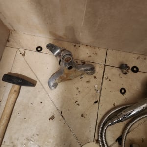 ברז חלוד, פטיש וצינור מתכת על רצפת אמבטיה