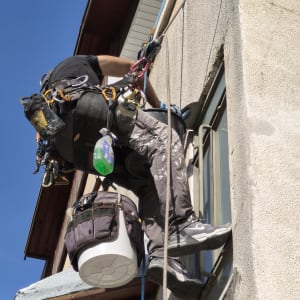 אדם מבצע עבודת איטום על קיר חיצוני של בניין