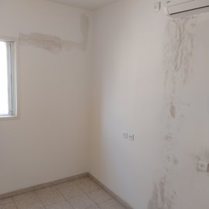 קיר עם תיקוני צבע וטיח ליד מזגן