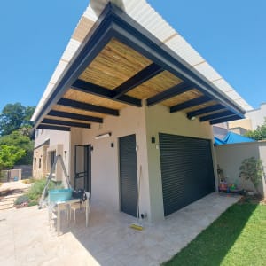 מרפסת עם גג עץ, שולחן, כיסאות וסולם.