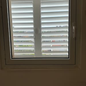 תריסים לבנים סגורים על חלון עם ידית בצד ימין