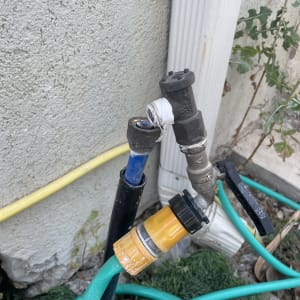 ברזים וצינור ירוק מחוברים לקיר חיצוני