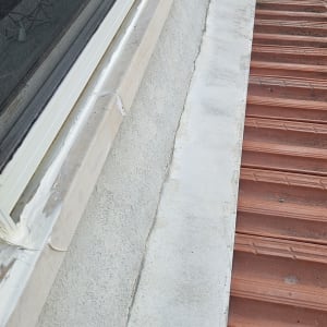 איטום חלון עם חומר איטום לבן על גג רעפים