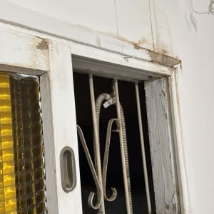 חלון ישן עם סורג מתכת וחלון זכוכית צהוב