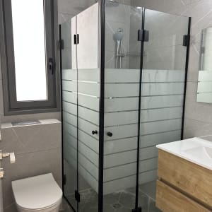 מקלחון זכוכית בחדר אמבטיה מודרני עם כיור ועץ
