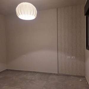 חדר ריק עם מנורה תלויה וקיר מעוצב