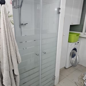 מקלחון זכוכית עם ראש מקלחת ומגבות תלויות