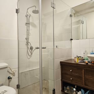 מקלחון זכוכית עם ראש מקלחת מתכתי ומדף קטן