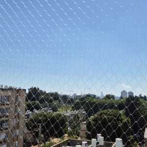 רשת יונים מותקנת על מרפסת עם נוף עירוני ברקע