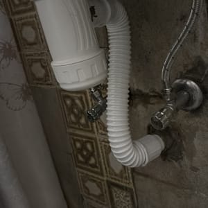 צינור ניקוז לבן מתחת לכיור עם ברזים