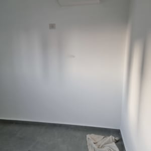 קיר ותקרה צבועים בלבן בחדר לאחר עבודת צביעה