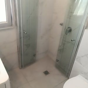 מקלחון עם דלתות זכוכית ומרצפות חדשות