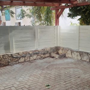 גדר עץ לבנה על בסיס אבן בחצר