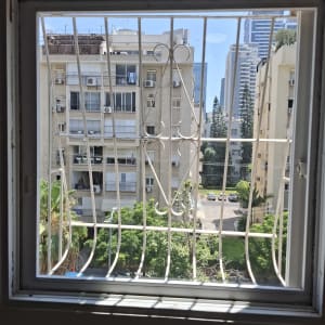 חלון עם סורגי מתכת ונוף עירוני ברקע