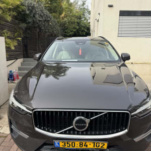 רכב וולוו חונה ליד בניין עם צמחייה ברקע