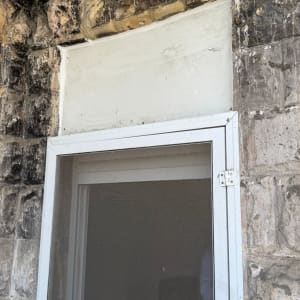 חלון עם מסגרת מתכת על קיר אבן ישן