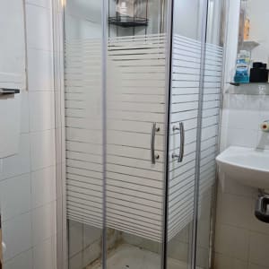 מקלחון זכוכית עם מדף ומוצרי רחצה