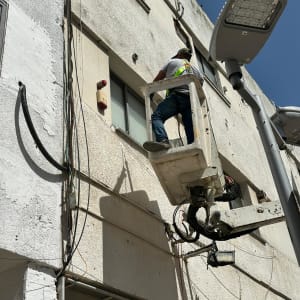 אדם בעבודה על בניין עם מנוף וסולמות