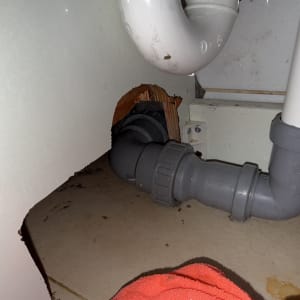 צנרת פלסטיק מתחת לכיור עם מגבת אדומה