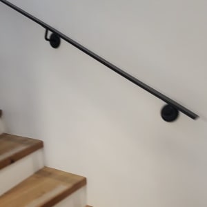 מדרגות עץ עם מעקה מתכת על קיר לבן