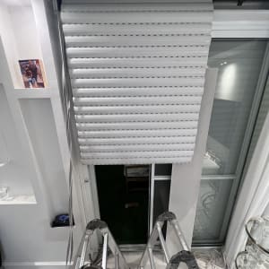 תריסים לבנים פתוחים למחצה עם סולם מתחתיהם