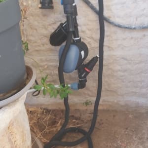 מערכת השקיה ליד עציץ על קיר אבן