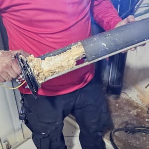 אדם מחזיק חלק של דוד שמש עם הצטברות אבנית