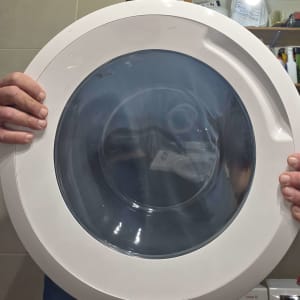 אדם מחזיק דלת מכונת כביסה בחדר כביסה