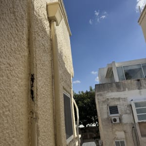 קיר חיצוני עם מזגן וצינור, שמיים כחולים