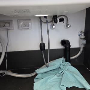 צינורות מתחת לכיור עם מגבת ירוקה