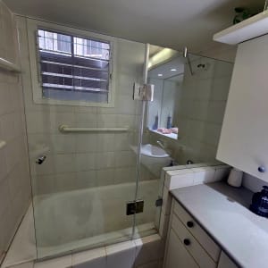 מקלחת עם דלת זכוכית וחלון קטן