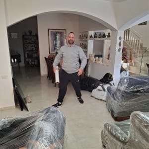 אדם בחדר עם רהיטים עטופים בניילון למעבר דירה