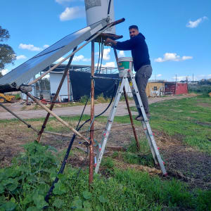 אדם על סולם מתקן דוד שמש בשטח פתוח