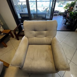 כורסה אפורה עם כתם על הרצפה ליד חלון גדול