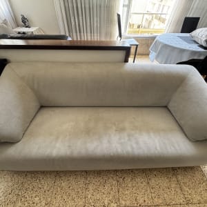 ספה אפורה בחדר עם שולחן וכיסאות ברקע