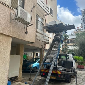 מנוף משאית מרים מזגן לקומה גבוהה בבניין