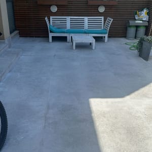 מרפסת עם ריצוף חדש, צינור ירוק ופח אשפה