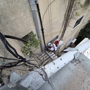 עובדים בגובה על קיר בניין עם ציוד בטיחות
